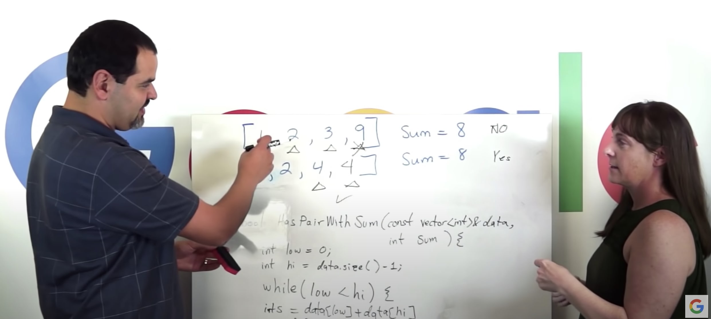 a man being interviewed by a women and using the whiteboard to write the solution to the coding challenge