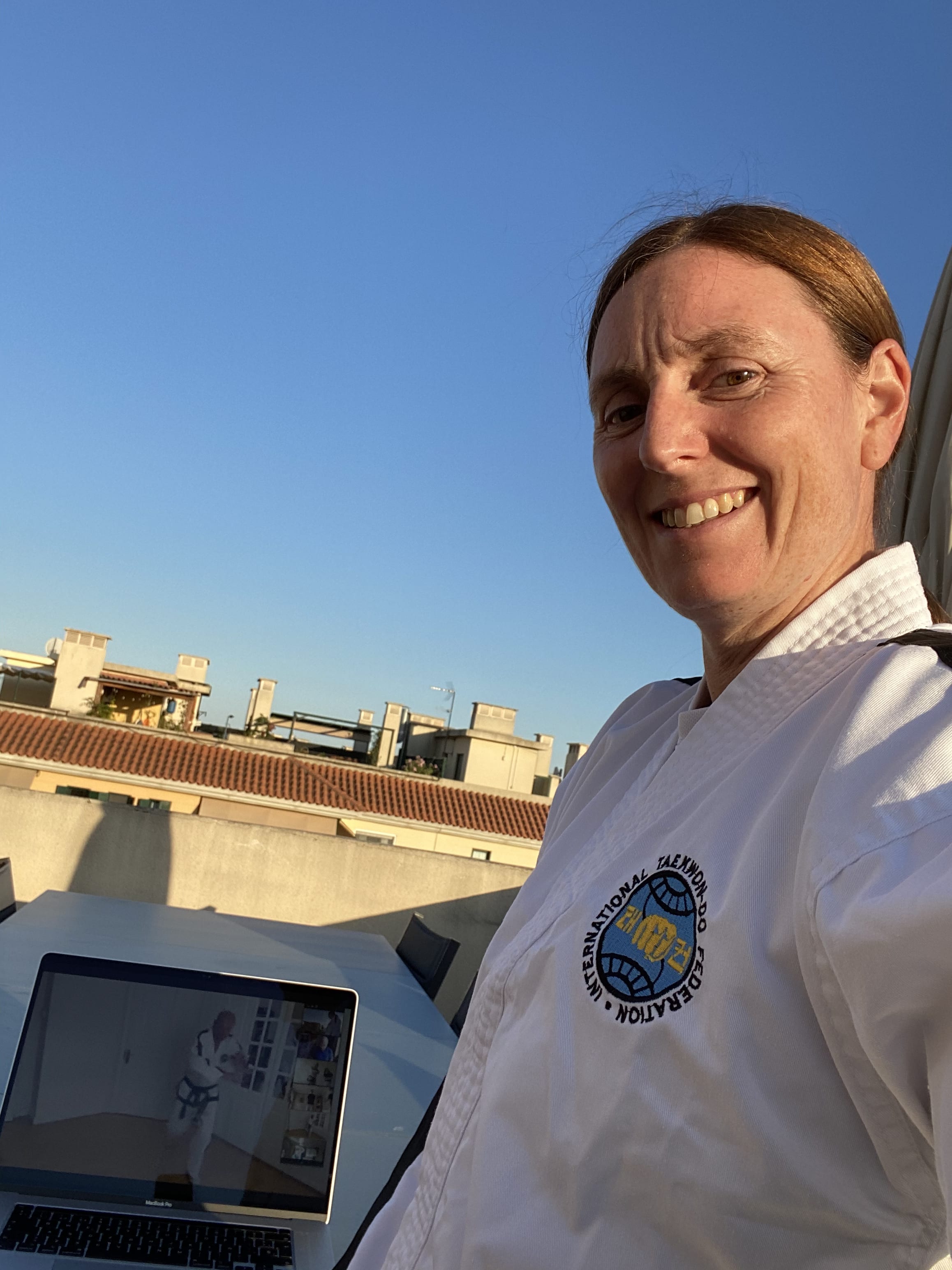 me doing taekwondo on the roof with the computer showing the zoom call for training