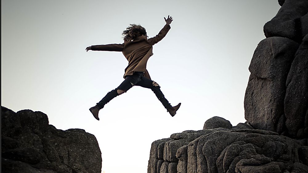 person leaping over a mountain