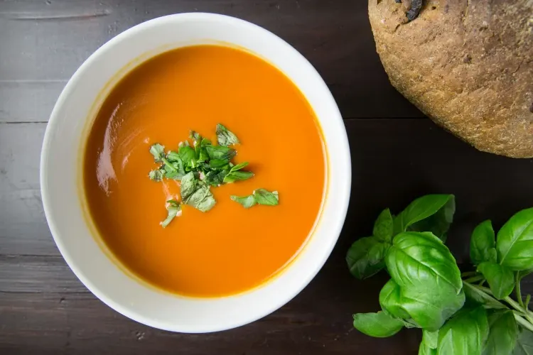 Tomato soup with a green leaf in a bowl.