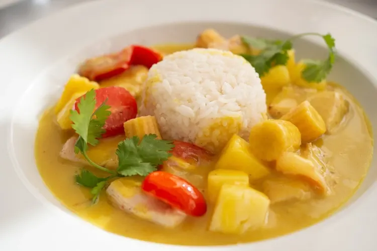 Yellow chicken curry served with white rice on a deep dish