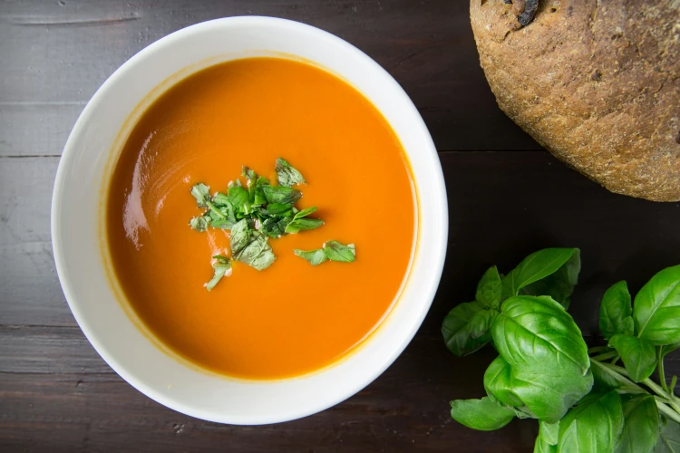 Tomato soup with a green leaf in a bowl.