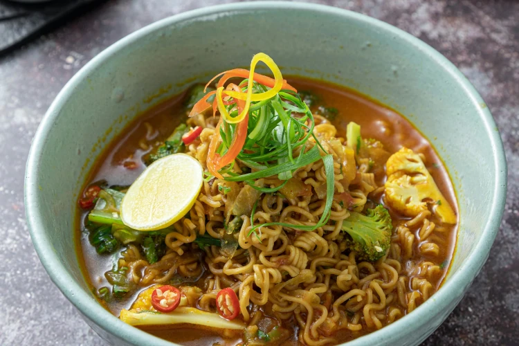Spicy noodle soup with vegetables showing in a bowl