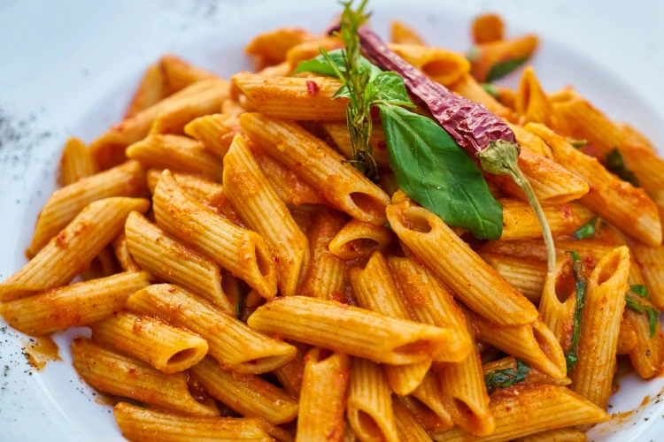 Spicy tomato pasta in a bowl with garnish on top