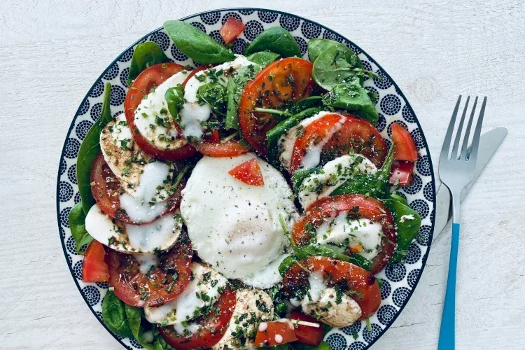 Caprese salad on a bowl with a fork beside it