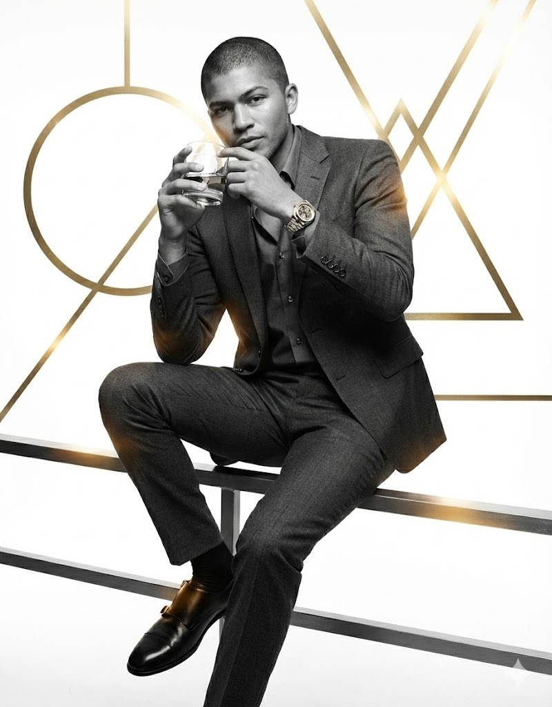 Generate a B&W picture of me following the prompt:
Character
A strong, athletic man - as per my picture - in his late 30s sits casually on a railing, one arm on his knee, the other raised near his face holding a glass of bourbon.
Clothing and Accessories
He wears a grey charcoal suit with a matching shirt, top button open, a silver and gold skeleton Rolex watch. black shoes with gold double buckle
Lighting Detail
Warm yellow and red reflections move across his suit and face, adding depth and a cinematic metallic glow.
Background
Clean white background with pure gold geometric shapes — circles, triangles, and lines — intersecting through the frame, blending modern design with luxury photography.
Style / Mood
Cinematic, masculine, modern. Editorial minimalism with a tone of quiet wealth and strength.