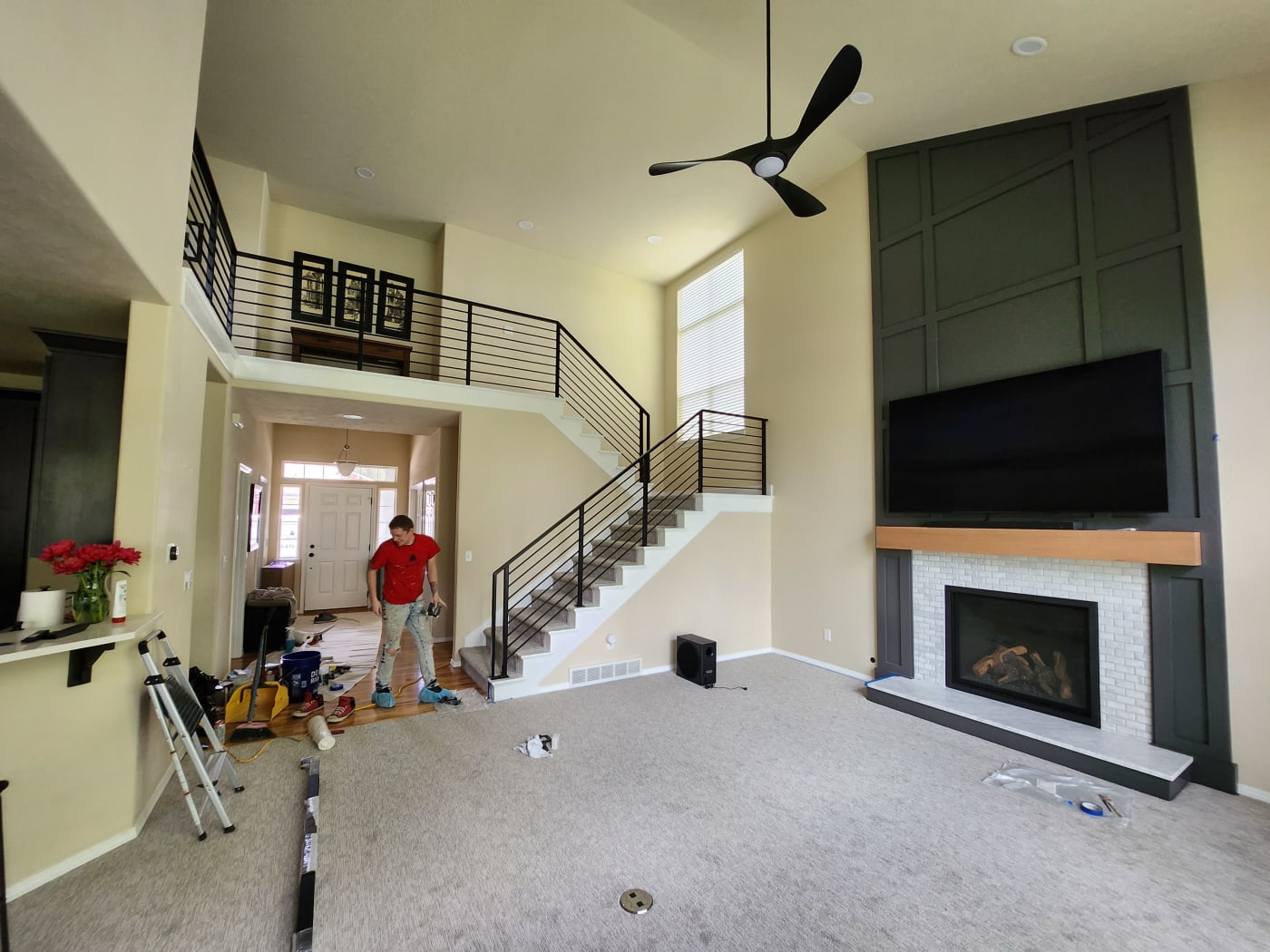 A worker in front of a freshly installed staircase and a custom fireplace in a newly remodeled Spokane Metro WA home. The clean lines of the modern staircase and the elegant fireplace surround showcase NIB’s attention to detail in transforming spaces while staying on schedule.