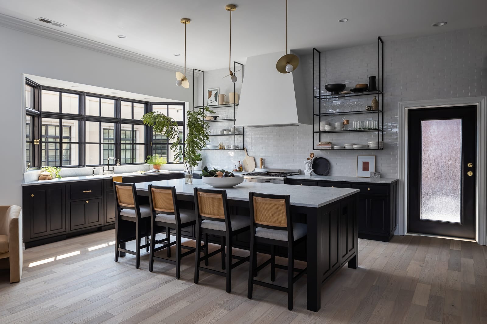 This kitchen remodel by NIB in Spokane, WA, features a blend of modern design elements and functional style. The sleek, black cabinetry contrasts beautifully with the light-colored wood floors, while the spacious island serves as both a prep area and a casual dining spot. Large, black-framed windows allow natural light to flood the space, making the room feel open and airy. With stylish pendant lights and an elegant backsplash, this kitchen balances aesthetics and practicality. The clean lines and thoughtful design choices reflect NIB’s expertise in crafting custom kitchen spaces.
