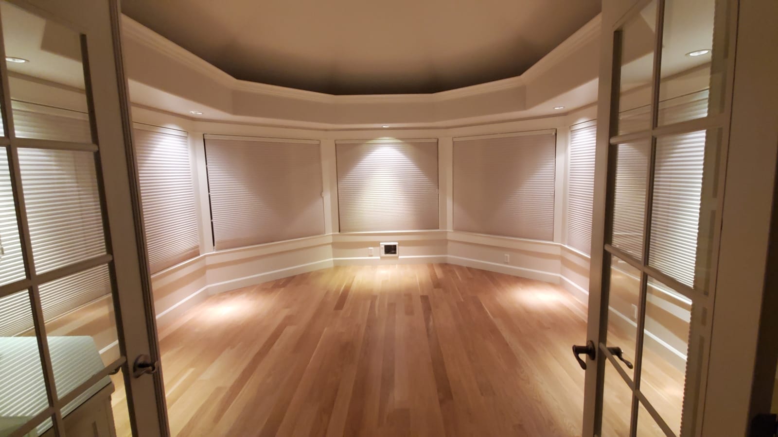 A beautifully finished, light-filled room in a Moran Prairie home in the Spokane, WA area, done by NIB. It features expansive windows with custom blinds and elegant hardwood floors. The room’s clean lines and smooth design, including recessed lighting and detailed crown molding, create a sophisticated atmosphere. This space reflects NIB's commitment to quality craftsmanship and meticulous attention to detail. 