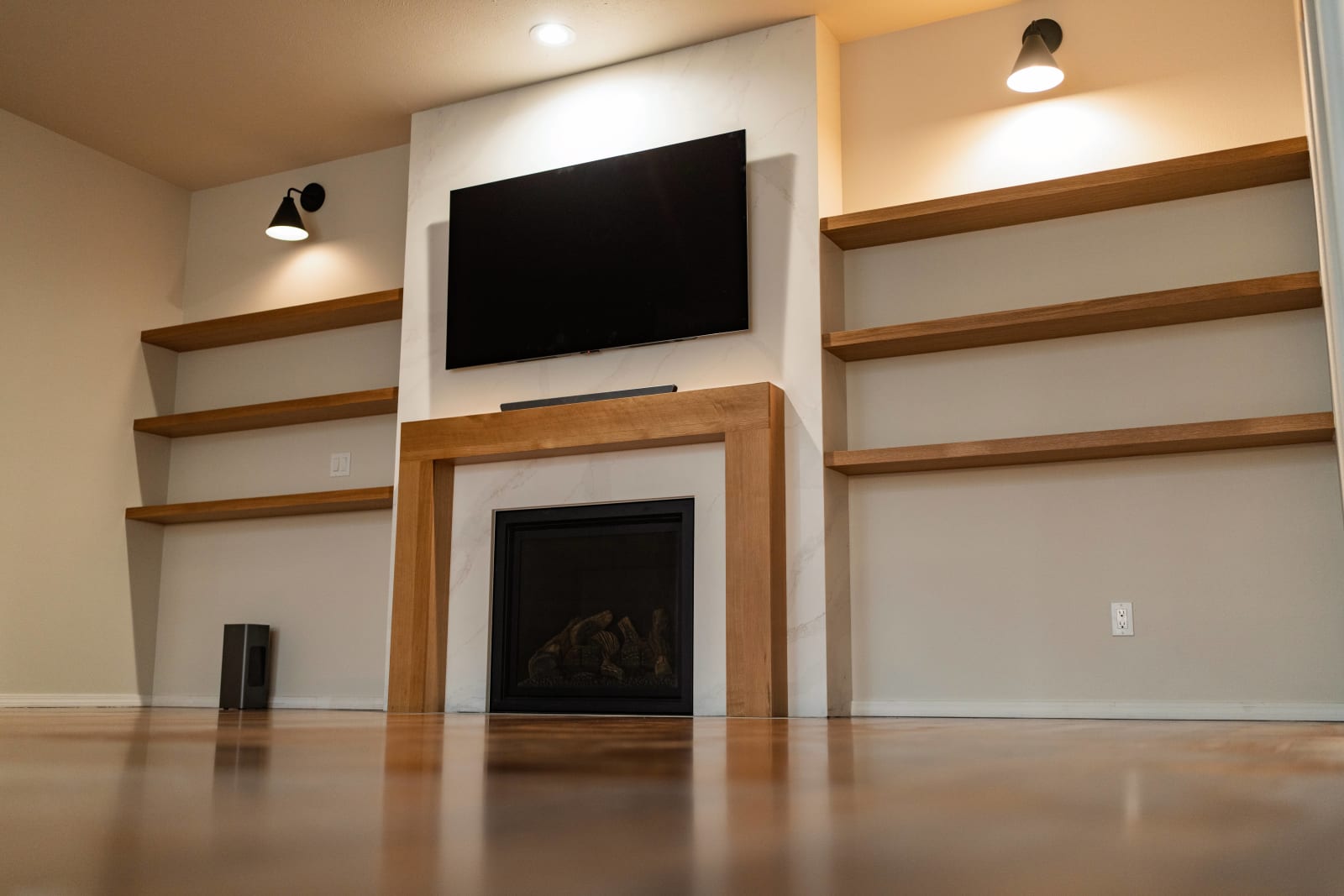 A sleek, modern interior remodel in the Spokane, WA area by NIB. The focal point is a beautifully designed wall unit featuring a built-in fireplace with a custom wood frame. Above the fireplace, a wall-mounted TV is framed by minimalist shelves, creating a balanced and functional layout. The clean lines, neutral colors, and high-quality materials highlight the craftsmanship and attention to detail NIB brings to every project, providing both comfort and style in the heart of the home.
