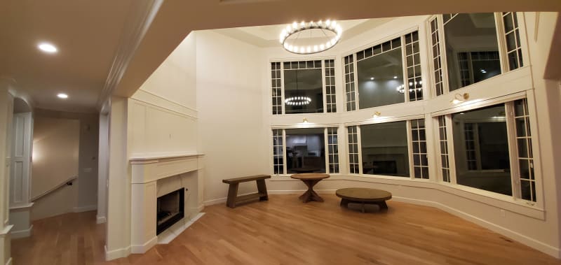 This residential interior project by NIB in Spokane, WA, features a cozy and inviting living space. The expansive bay window allows plenty of natural light to pour in, offering stunning views and creating a bright, airy atmosphere. The elegant fireplace, framed with white paneling, adds warmth and a touch of sophistication to the room. The light wood flooring contrasts beautifully with the clean lines of the architecture, while the modern lighting fixtures above and below further enhance the space. NIB’s attention to detail is evident in the seamless blend of style and functionality throughout this living area.