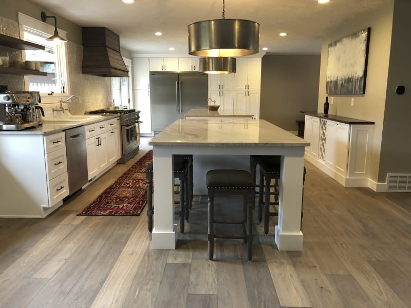 This kitchen remodel by NIB in Spokane, WA, beautifully blends modern finishes with a welcoming and functional layout. The spacious center island, complete with sleek countertops and comfortable seating, makes it an ideal space for both cooking and entertaining. The natural light streaming through the windows highlights the high-end appliances, including the professional range and refrigerator, while the contrasting cabinetry adds a touch of sophistication. The warm wood flooring and detailed cabinetry complete the inviting atmosphere of this thoughtfully designed kitchen.