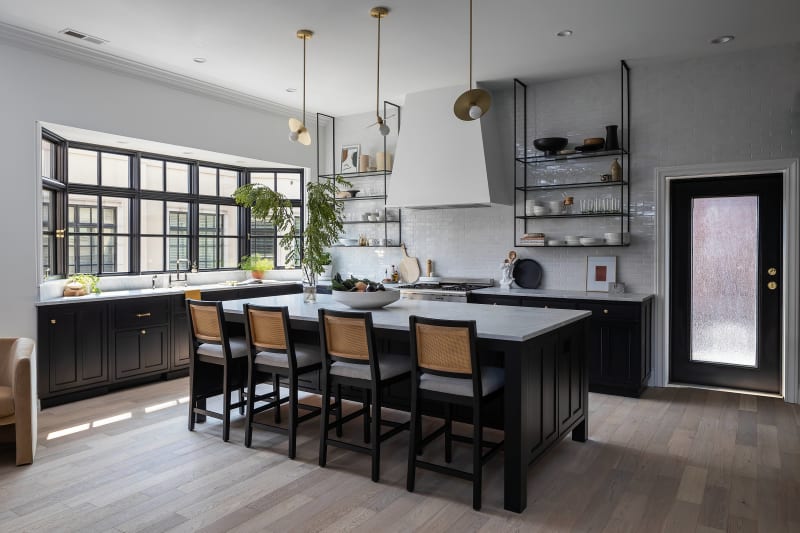 This stunning kitchen remodel by NIB in Spokane, WA, beautifully blends contemporary design with timeless appeal. The sleek black cabinetry contrasts elegantly with the white subway tile backsplash and marble countertops. Open shelving adds an airy feel, showcasing carefully curated dinnerware and décor. The island, perfect for both meal prep and social gatherings, is paired with stylish bar stools. Natural light floods the space through expansive windows, creating a bright and inviting atmosphere that enhances the entire cooking and dining experience.
