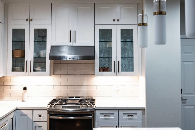 This is an elegant kitchen remodel in Spokane, WA, completed by NIB. The updated space features clean lines with classic white cabinetry, sleek countertops, and modern appliances, offering a timeless yet functional design. Glass-front cabinets provide a stylish way to display glassware, while the warm light under the cabinets adds ambiance and highlights the details. The updated space allows for a perfect balance of both form and function, providing the homeowners with a welcoming area for cooking and gathering.