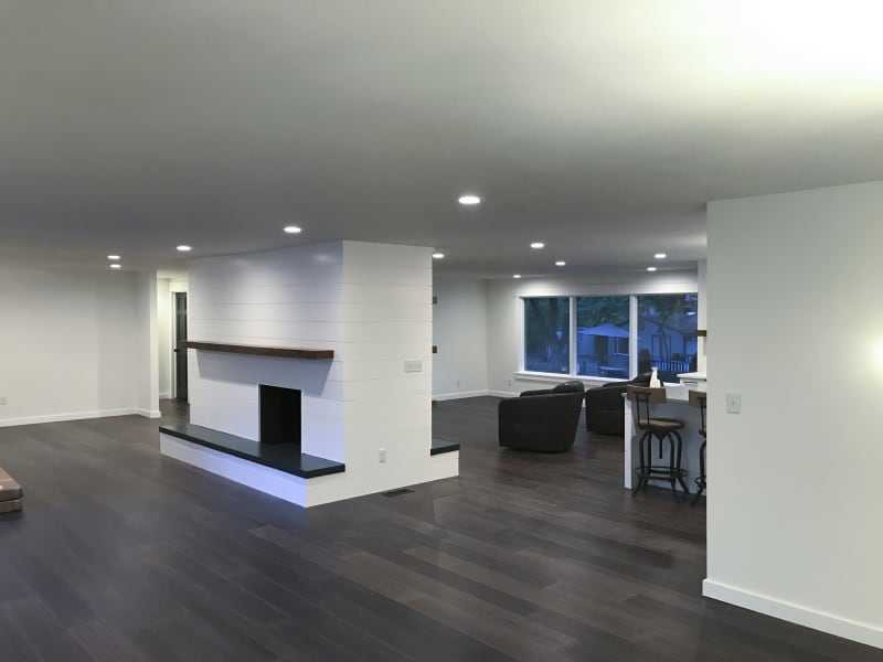This inviting bedroom features custom paneling on the accent wall installed by NIB in Spokane, WA. The neutral tones of the paint and the luxurious textures of the bedding and pillows create a serene and restful atmosphere. The design, complemented by elegant nightstands and soft lighting, transforms the space into a comfortable retreat, balancing both style and function. The subtle details, like the clean lines of the paneling and the warm wood flooring, provide a perfect backdrop for relaxation.