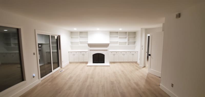 This inviting bedroom features custom paneling on the accent wall installed by NIB in Spokane, WA. The neutral tones of the paint and the luxurious textures of the bedding and pillows create a serene and restful atmosphere. The design, complemented by elegant nightstands and soft lighting, transforms the space into a comfortable retreat, balancing both style and function. The subtle details, like the clean lines of the paneling and the warm wood flooring, provide a perfect backdrop for relaxation.