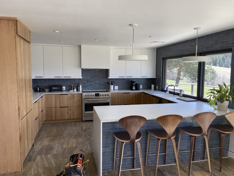This inviting bedroom features custom paneling on the accent wall installed by NIB in Spokane, WA. The neutral tones of the paint and the luxurious textures of the bedding and pillows create a serene and restful atmosphere. The design, complemented by elegant nightstands and soft lighting, transforms the space into a comfortable retreat, balancing both style and function. The subtle details, like the clean lines of the paneling and the warm wood flooring, provide a perfect backdrop for relaxation.