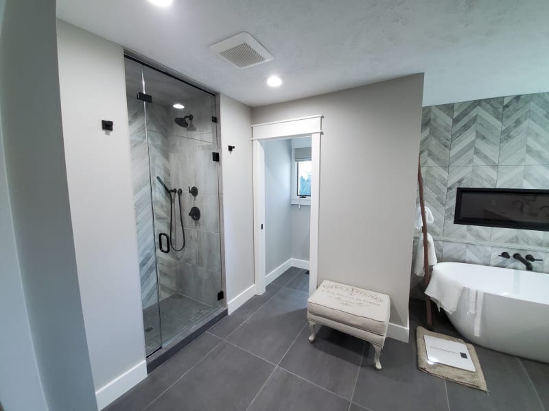 This inviting bedroom features custom paneling on the accent wall installed by NIB in Spokane, WA. The neutral tones of the paint and the luxurious textures of the bedding and pillows create a serene and restful atmosphere. The design, complemented by elegant nightstands and soft lighting, transforms the space into a comfortable retreat, balancing both style and function. The subtle details, like the clean lines of the paneling and the warm wood flooring, provide a perfect backdrop for relaxation.