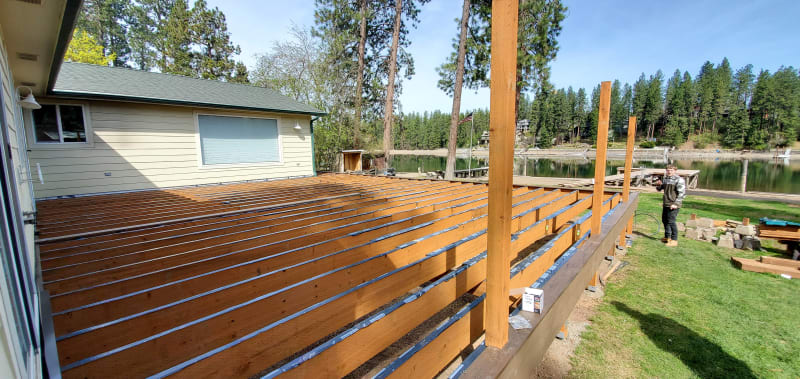 A beautifully framed deck nearing completion, with the NIB team working in Spokane, WA. The perfect layout is visible with pressure-treated beams and joists, and the stunning view of the lake adds a serene touch to the project. This carefully planned and executed deck will soon serve as a space for outdoor gatherings, blending quality craftsmanship with nature’s beauty. 