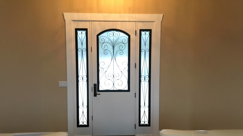 This stunning entryway was installed by NIB in Spokane, WA. The decorative glass panels on either side of the door not only add elegance but also let natural light pour into the space. The intricate black metalwork on the glass pairs beautifully with the white framing, creating a balanced, timeless look. NIB's expert craftsmanship shines in every detail, from the smooth door finish to the precise installation of the glass inserts, ensuring both beauty and security.
