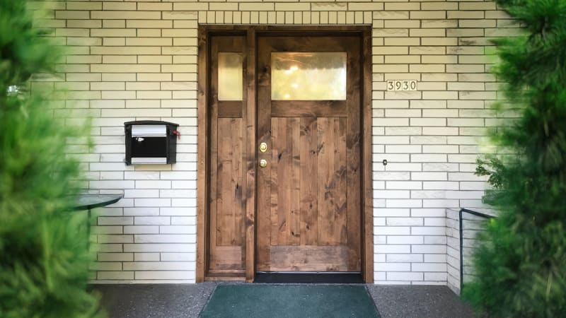 This beautifully updated front entryway, completed by NIB in Spokane, WA, features a striking wooden double door set against a clean, classic white brick backdrop. The natural wood doors provide a warm, inviting entrance to the home, offering both charm and durability. The simple yet sophisticated design of the brickwork and the stylish hardware on the doors create an elegant first impression. NIB's expert installation of both the doors and windows contributes to the refined aesthetic, enhancing the home’s curb appeal.