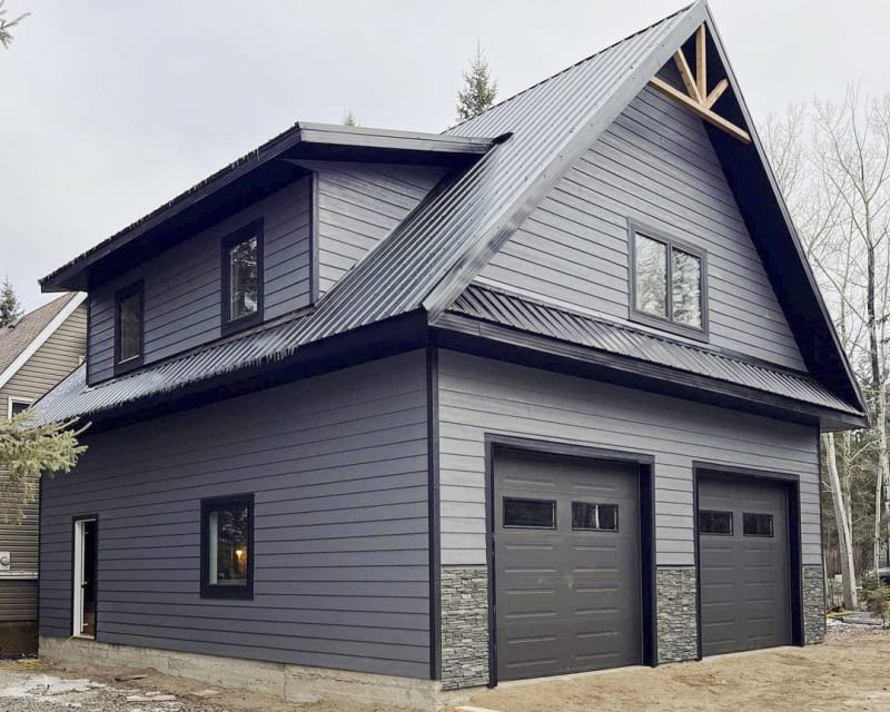 Completed siding installation project by NIB in Spokane, WA, features the modern aesthetic of LP SmartSide siding, which is both durable and visually appealing. The combination of dark tones and sharp lines gives the building a sleek, contemporary look. The contrasting garage doors and roof design further enhance the structure’s architectural appeal, creating a clean, professional finish. NIB’s attention to detail ensures both beauty and functionality, with materials that are built to last and withstand the elements.