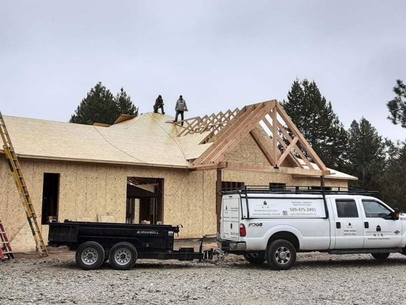 A custom home construction project in the Spokane, WA area, done by NIB. The building in its early stages. The roof is finished, and Styrofoam insulation is applied to the exterior walls, while the siding installation is still in progress.