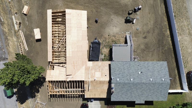 An aerial view of a custom home or additions construction project in Spokane, WA, by NIB. Showing the ongoing framing work and plywood installation on the roof. 