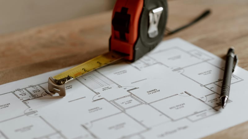 This image captures the essential tools used in the planning, bidding, and budgeting phase of custom home construction. A tape measure rests on detailed architectural blueprints, with the dimensions of various rooms clearly marked. The combination of the tape measure, pen, and the well-organized blueprint showcases the accuracy and precision required in planning a custom home. NIB’s expertise in ensuring the project stays within budget and on schedule is key to the seamless delivery of high-quality custom homes in the Spokane, WA, area.