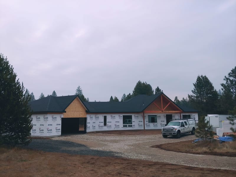 Exterior view of a custom home being built in Spokane, WA, by NIB, who is also overseeing the project. The home is in the framing stage, with the Tyvek house wrap installed for insulation and protection. The work is progressing smoothly, with attention to detail as the exterior comes together. NIB’s team is committed to providing exceptional craftsmanship and ensuring that every step of the construction process meets the highest standards.