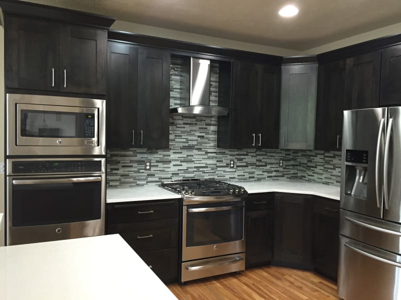 An elegant, fully renovated kitchen in a South Hill home in the Spokane, WA, area, done by NIB. It features rich dark wood cabinetry, stainless steel appliances, and a beautiful mosaic tile backsplash. The sleek countertops and modern finishes create a sophisticated, open space that’s both functional and stylish. This kitchen is the perfect blend of contemporary design and everyday practicality.