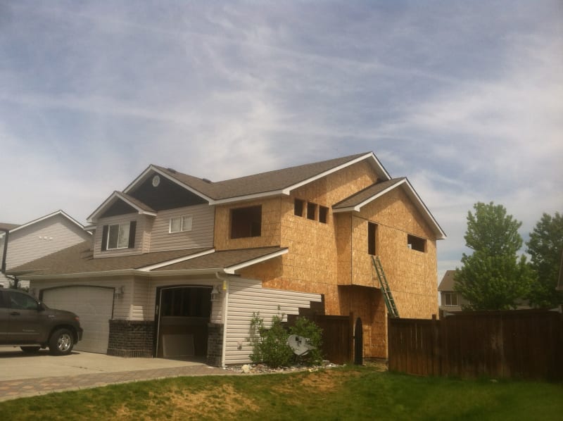 A home in the South Hill area of Spokane, WA,  under construction, showing the framework of an addition with exposed plywood sheathing and windows yet to be installed. Project by NIB. The image captures the early stages of a remodeling project, with visible work in progress and tools around the site. This photo reflects NIB’s commitment to quality craftsmanship in both new construction and home additions.