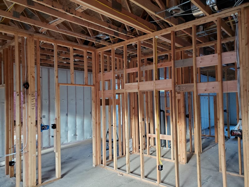 Curved wooden staircase in the framing stage of a custom home construction project by NIB in Spokane, WA. The staircase is being installed amidst exposed framing with surrounding walls in the early stages of construction. The woodwork on the staircase is visible as it begins to take shape, showcasing the craftsmanship of the build.
