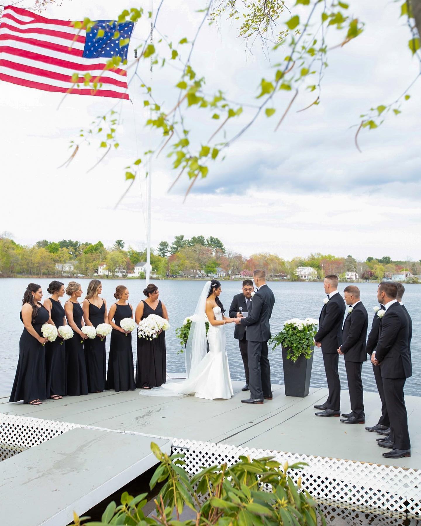 Lakeside wedding ceremony with white bridesmaid bouquets and ceremony flowers by Designs By Don Florist.
