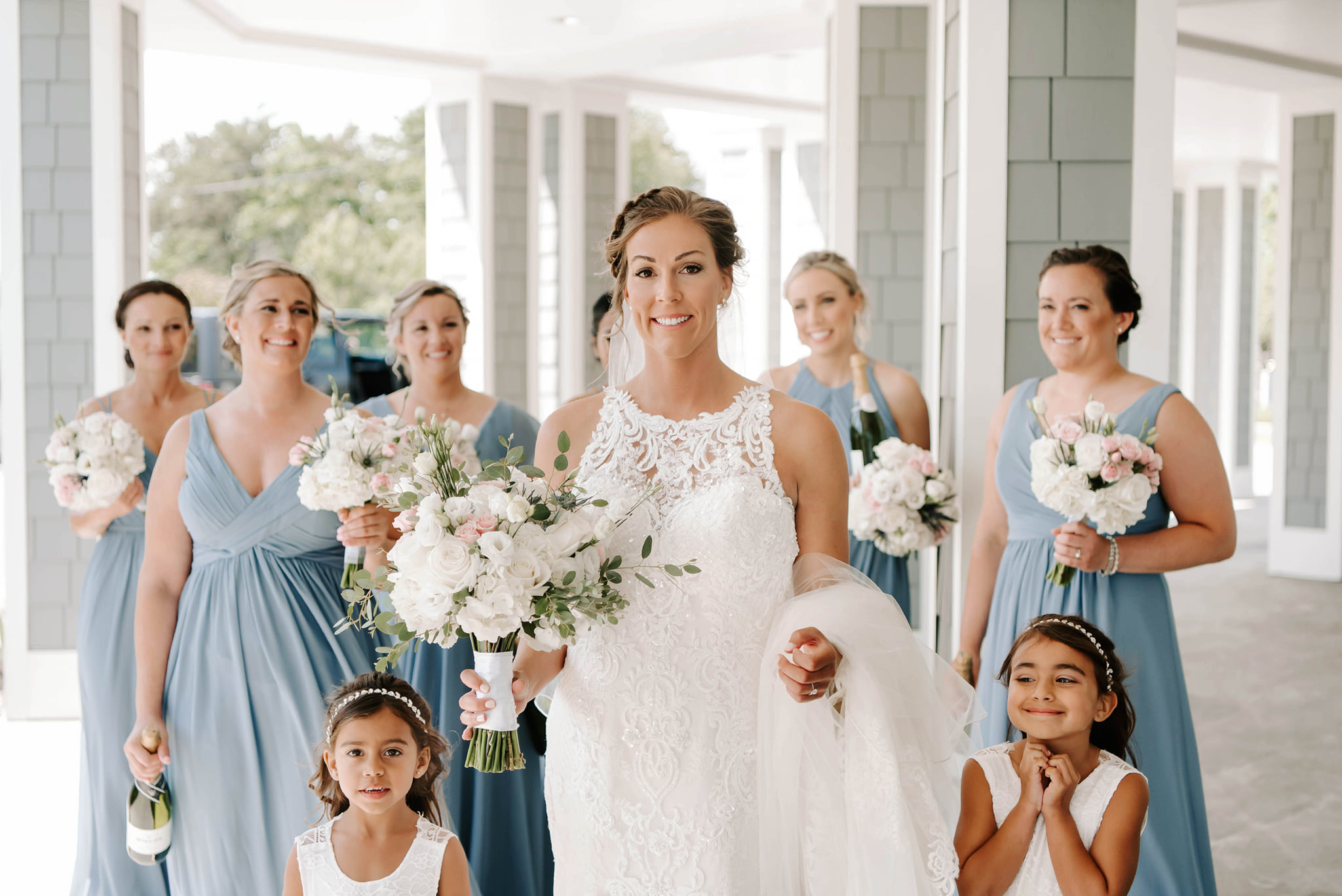 Bride and bridesmaids holding white and blush wedding bouquets by Designs By Don Florist.