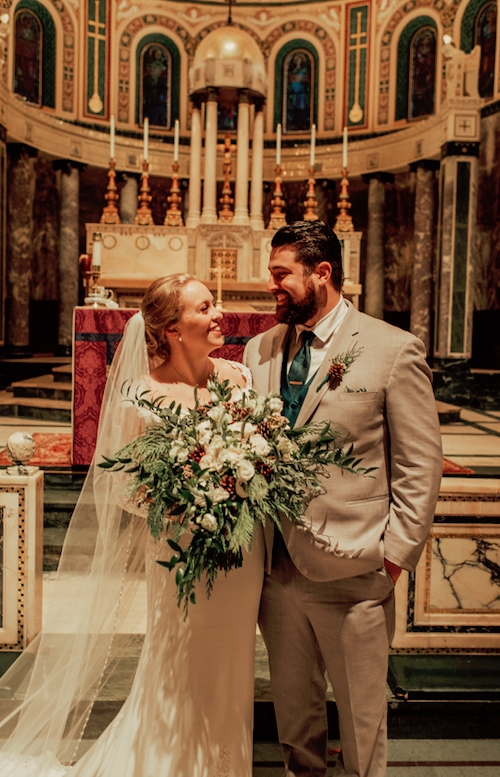 Bride with a lush greenery bridal bouquet during a church wedding by Designs By Don Florist.