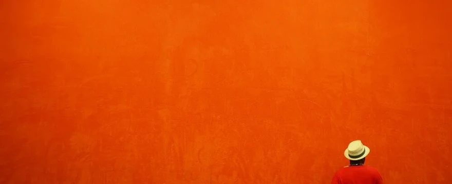 Single small figure standing in a vast empty landscape or minimal background, surrounded by negative space