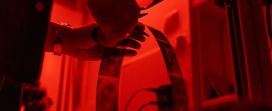 Film negatives hanging to dry in a darkroom, or a lab technician scanning film