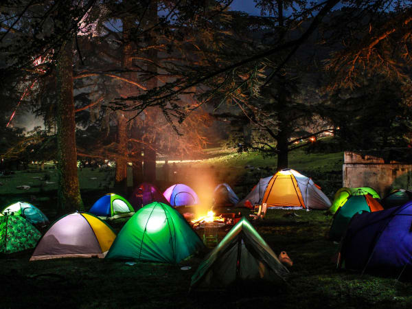 Des tentes en montagne autour d'un feu de camp