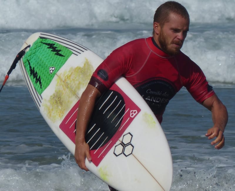 Surfeur sortant de l'eau avec sa planche de surf