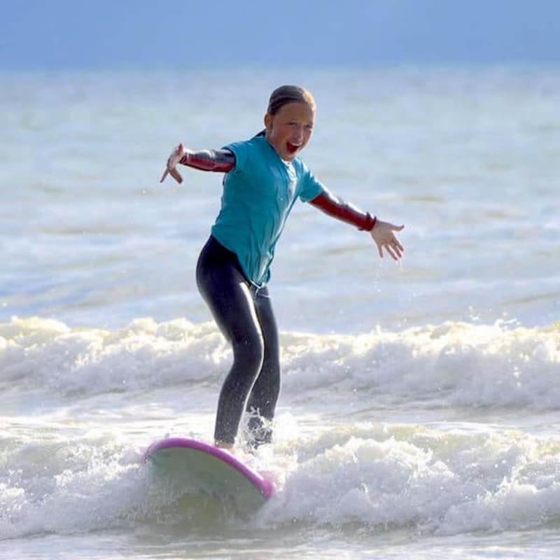 Enfant souriant sur une vague en surf à Mimizan