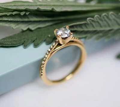 Un compromiso radiante se manifiesta en nuestra sortija en oro 18k, con un halo pavé que resalta el brillo del diamante central.