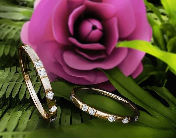 Joyas rodeadas por hojas y una rosa rosada
