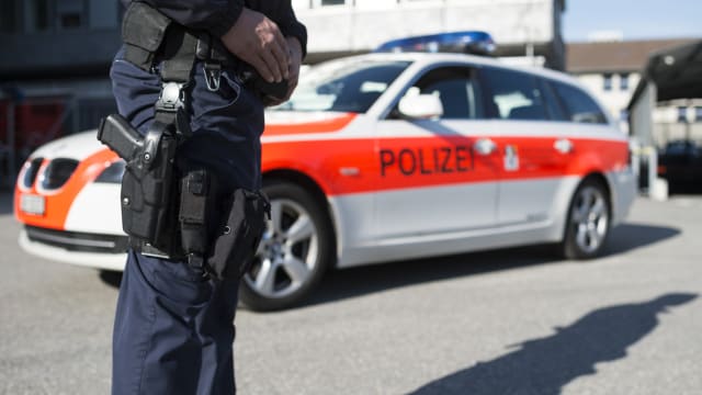 Ein Polizist steht vor einem Dienstfahrzeug der Kantonspolizei Graubünden, aufgenommen am Dienstag, 21. April 2015, in Chur. (KEYSTONE/Gian Ehrenzeller)
