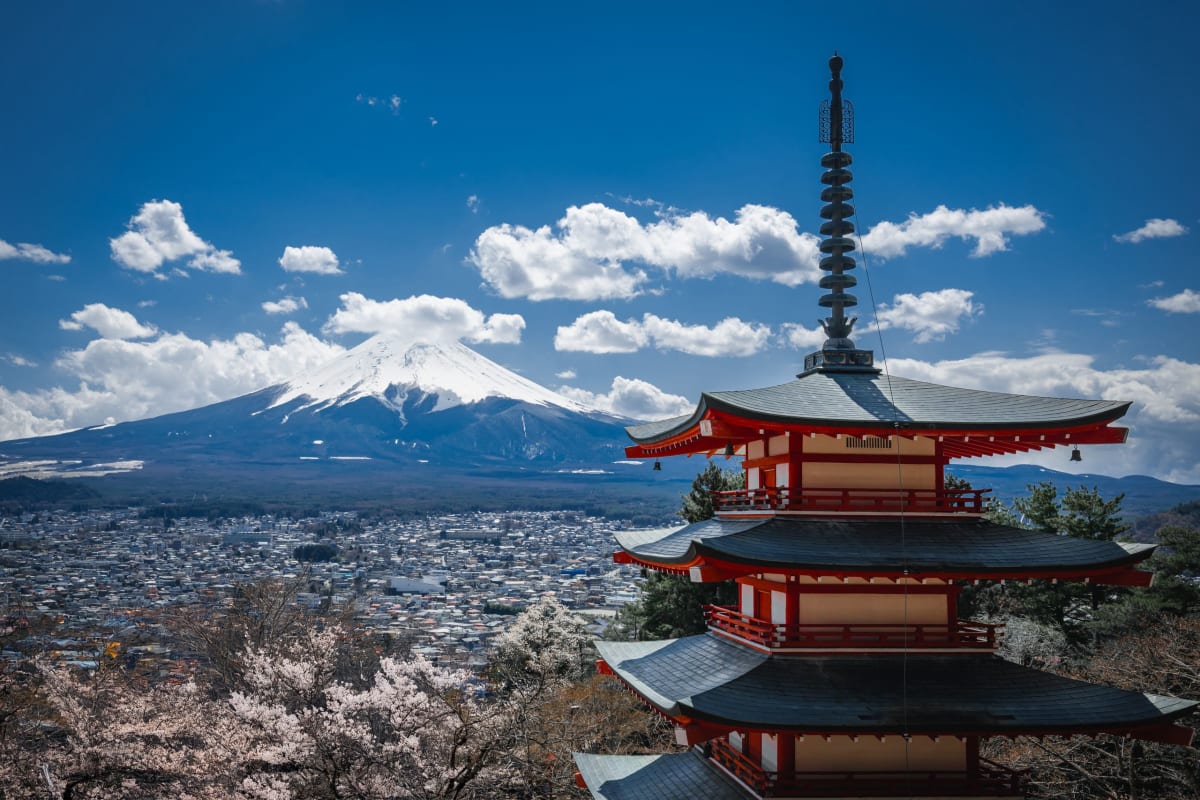 The red Chureito Pagoda framed by blooming cherry trees with snow-capped Mount Fuji in the background