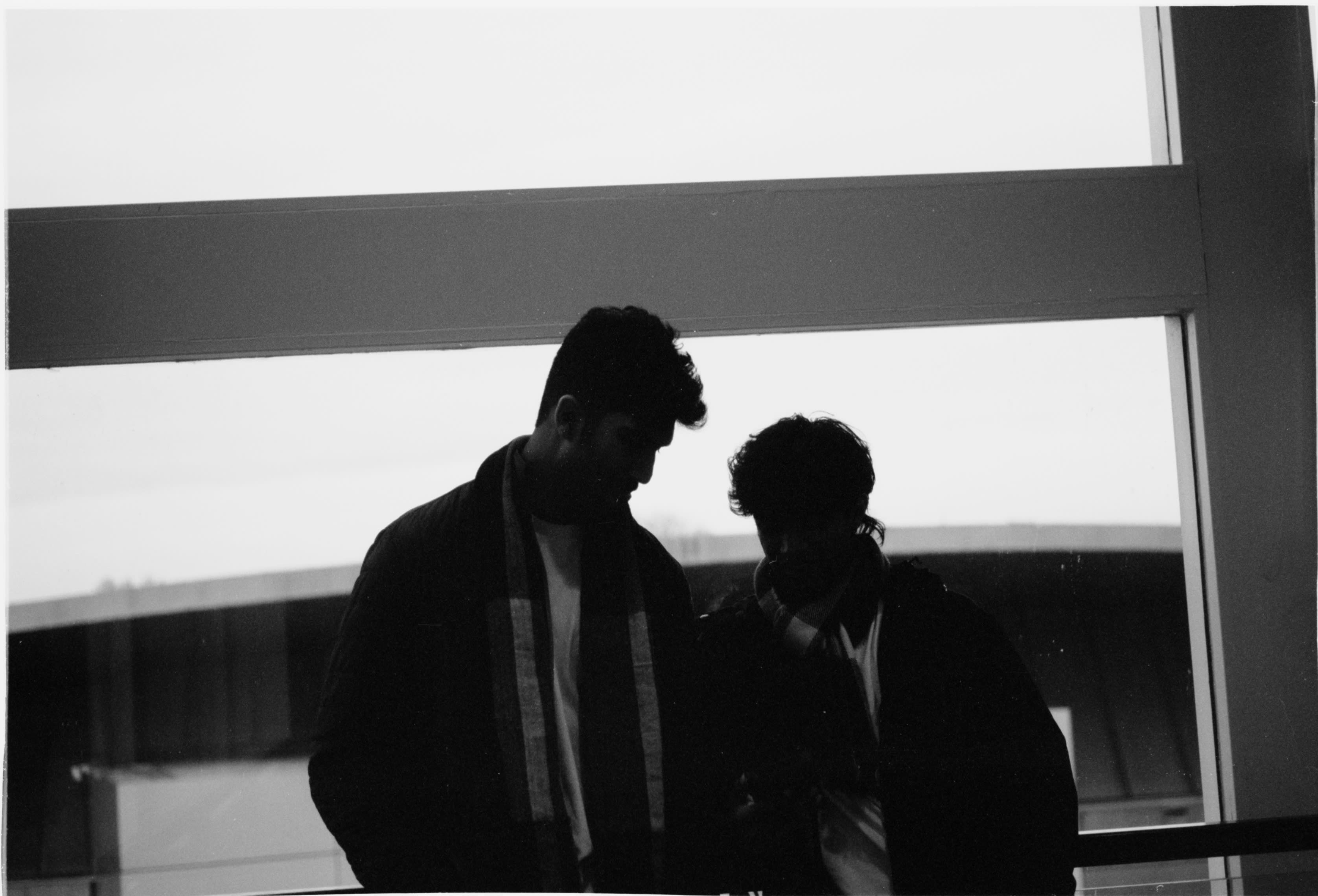 Two friends silhouetted against a large window