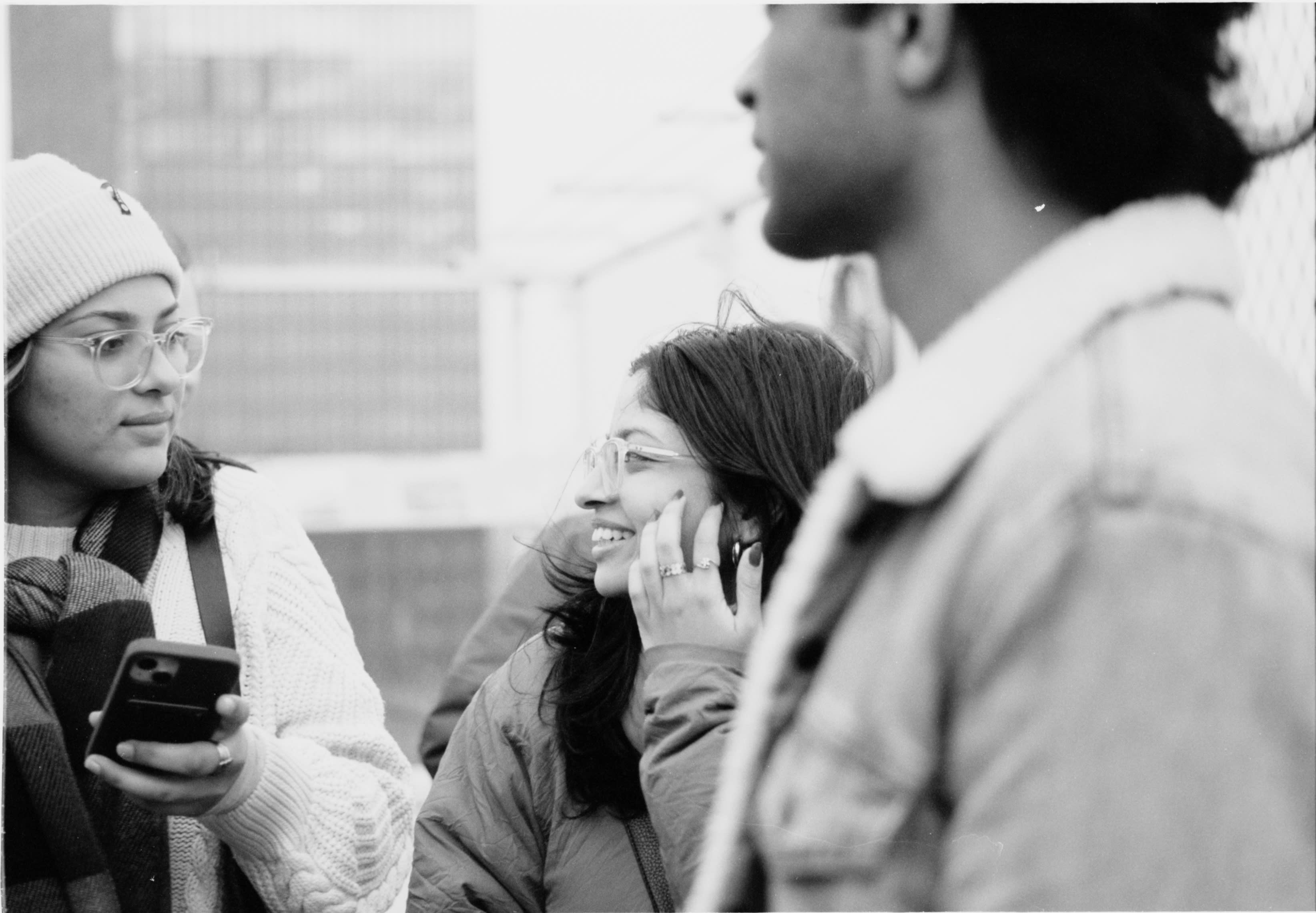 Friends talking outside, one on a phone call, with office towers behind