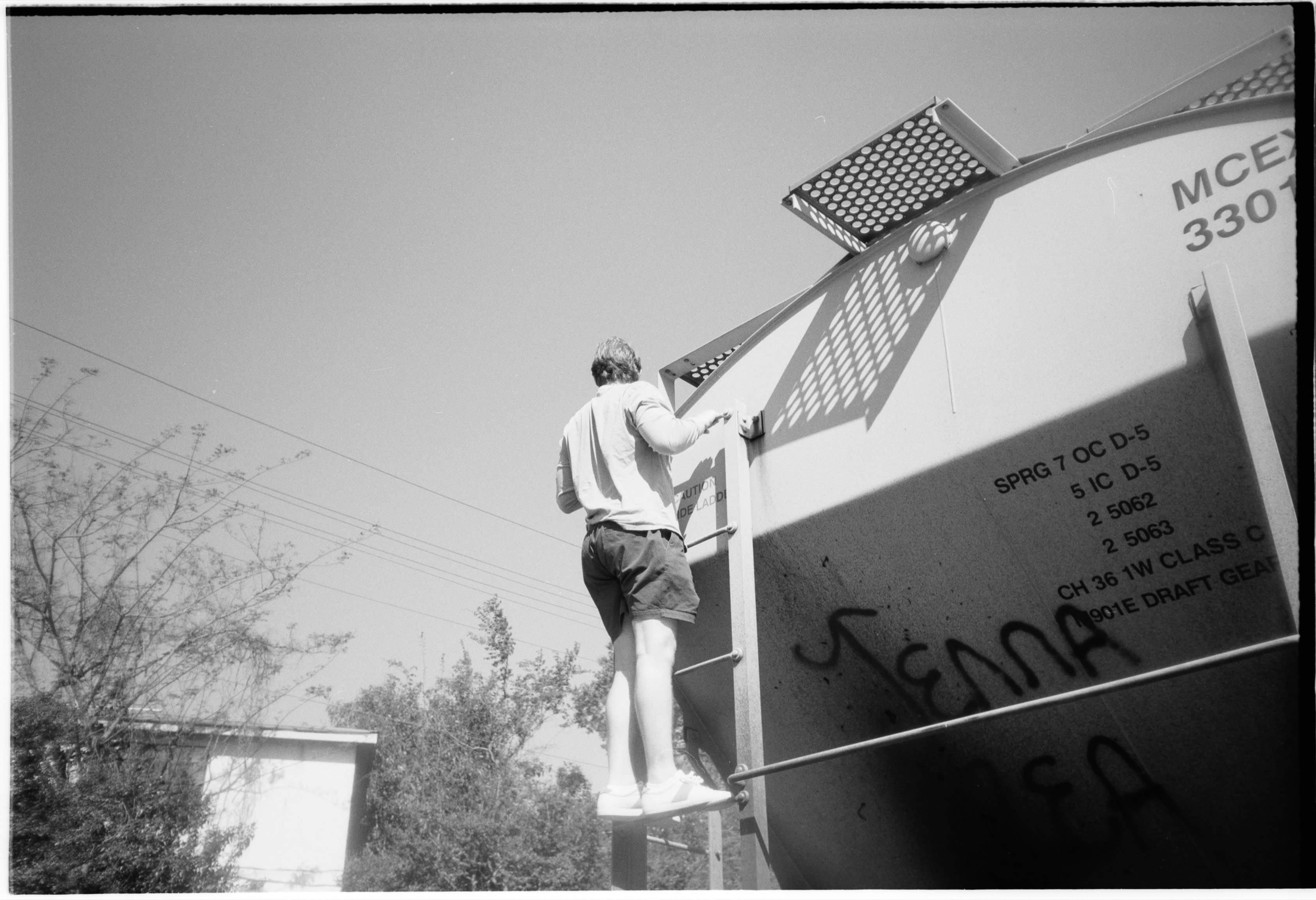 A friend climbing the ladder on the side of a graffitied rail car