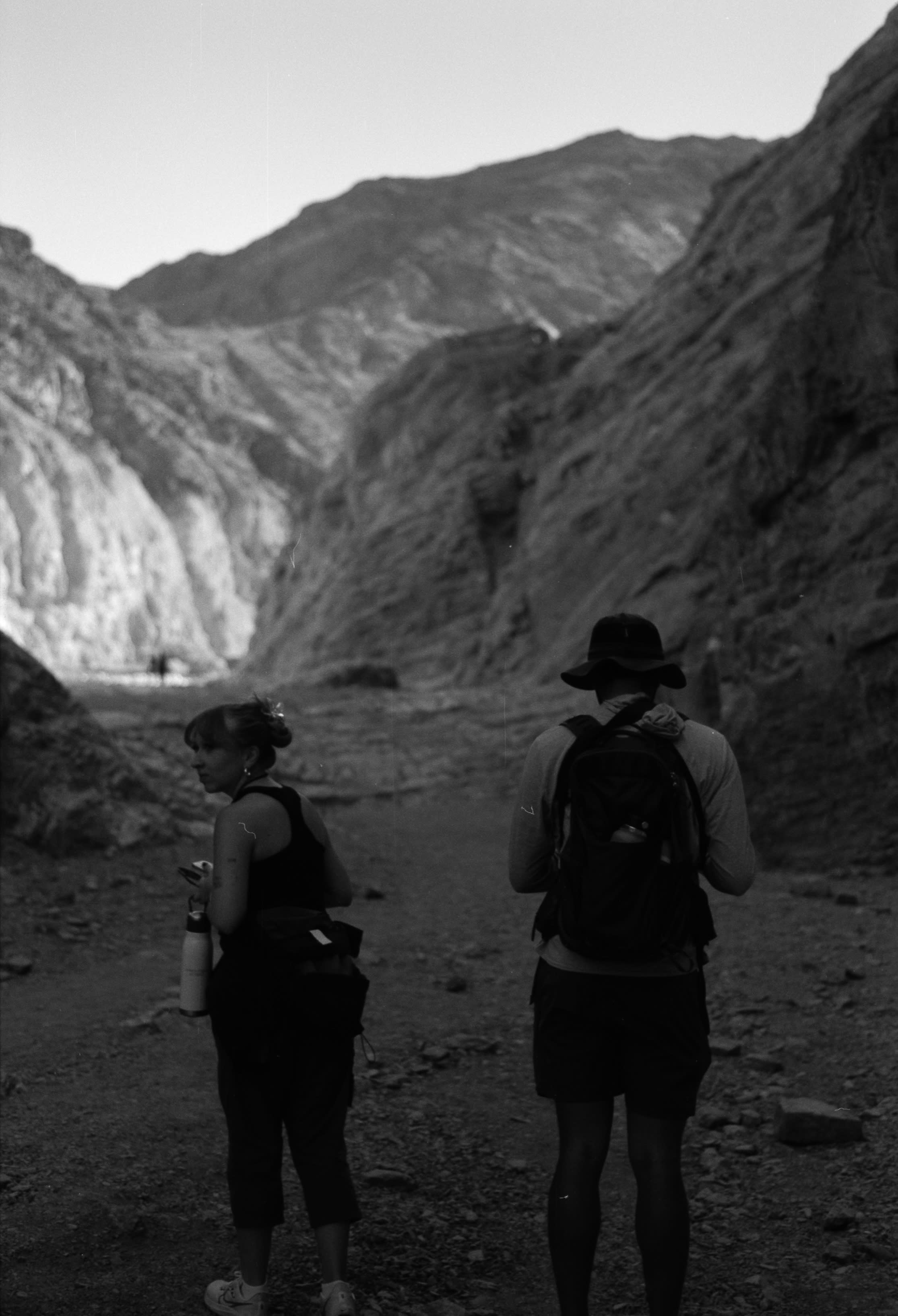 Two hikers in hats walking into a desert canyon