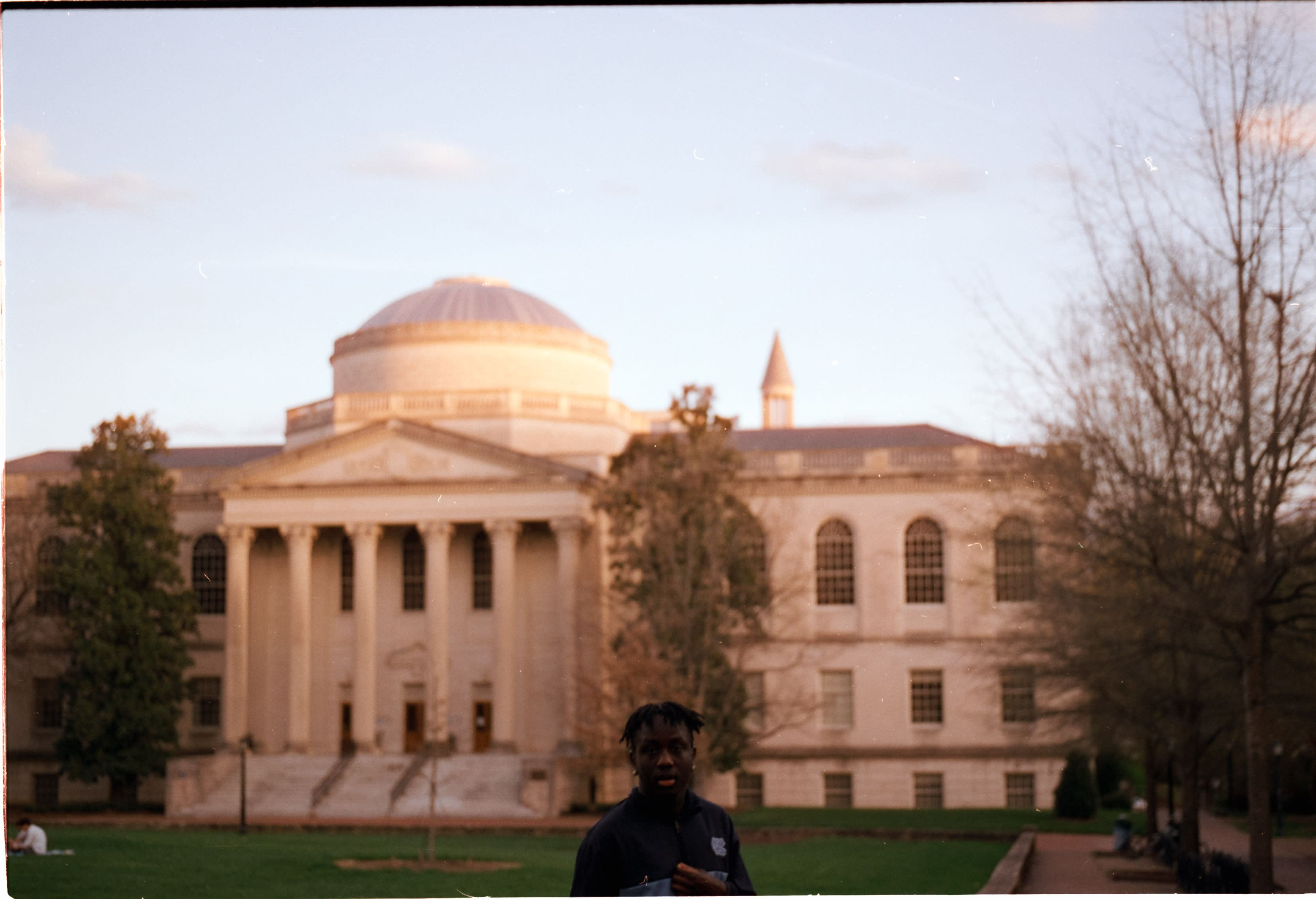 Wilson Library in golden-hour light, with a passerby in the foreground
